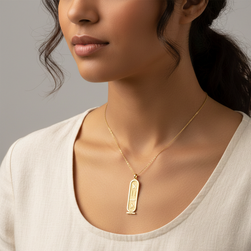 Woman wearing a gold necklace with a pendant against a neutral background