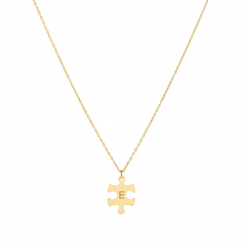 Gold necklace with a puzzle piece pendant on a white background
