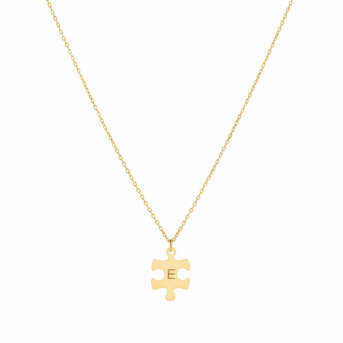 Gold necklace with a puzzle piece pendant on a white background