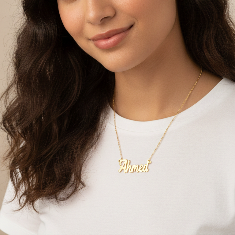 Woman wearing a gold necklace with 'Ahmed' on it against a neutral background